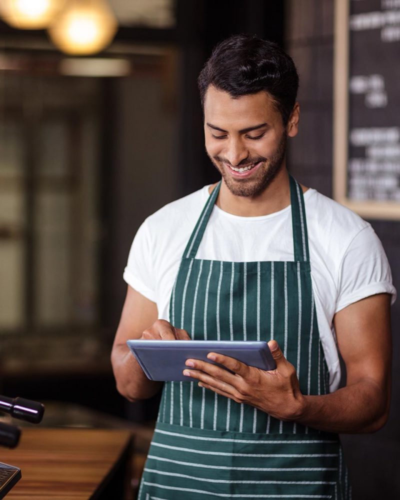 smiling-barista-using-tablet-in-the-bar-PPES8JB.jpg